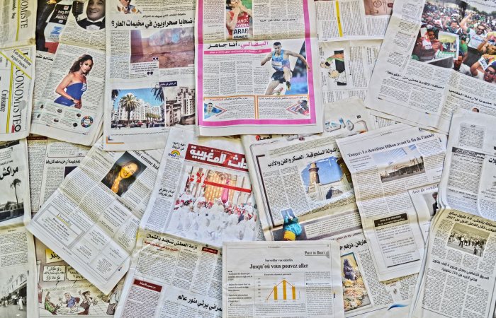A vibrant array of newspapers laid out in Fès, showcasing diverse stories.