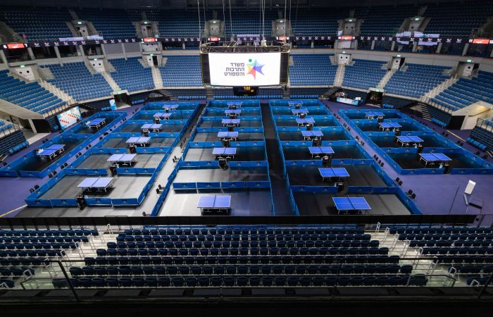 Aerial view of a large arena set up for a table tennis tournament with multiple tables.