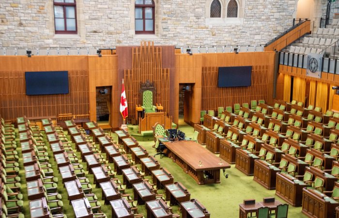 Interior view of the Canadian House of Commons with green seating and wooden decor.