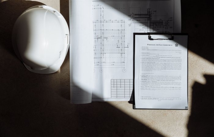 Top view of construction documents and hard hat in sunlight, capturing planning essence.